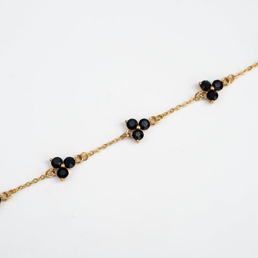 Gold chain bracelet with black gemstones on a background