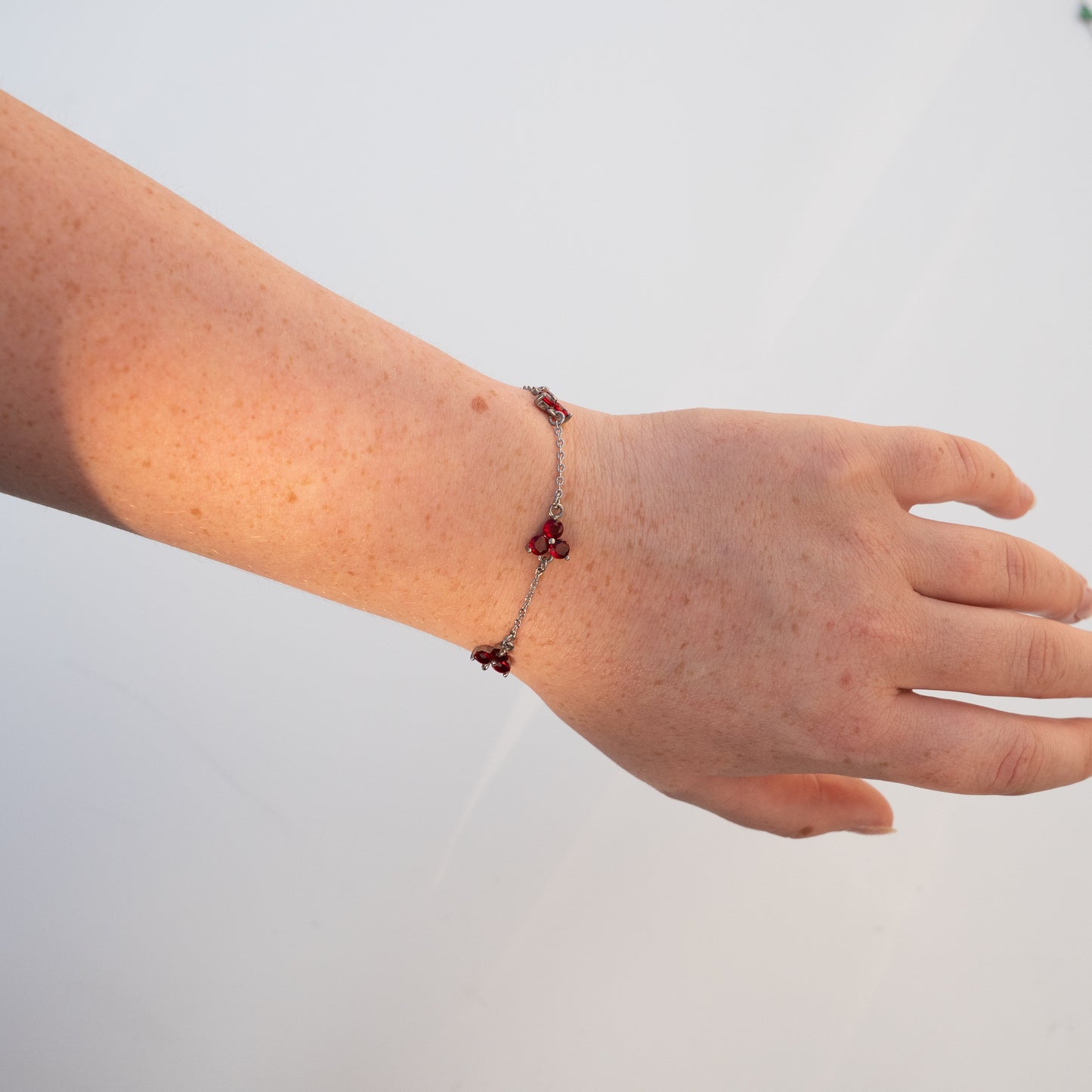 Hand wearing a silver bracelet with red beads on a light background