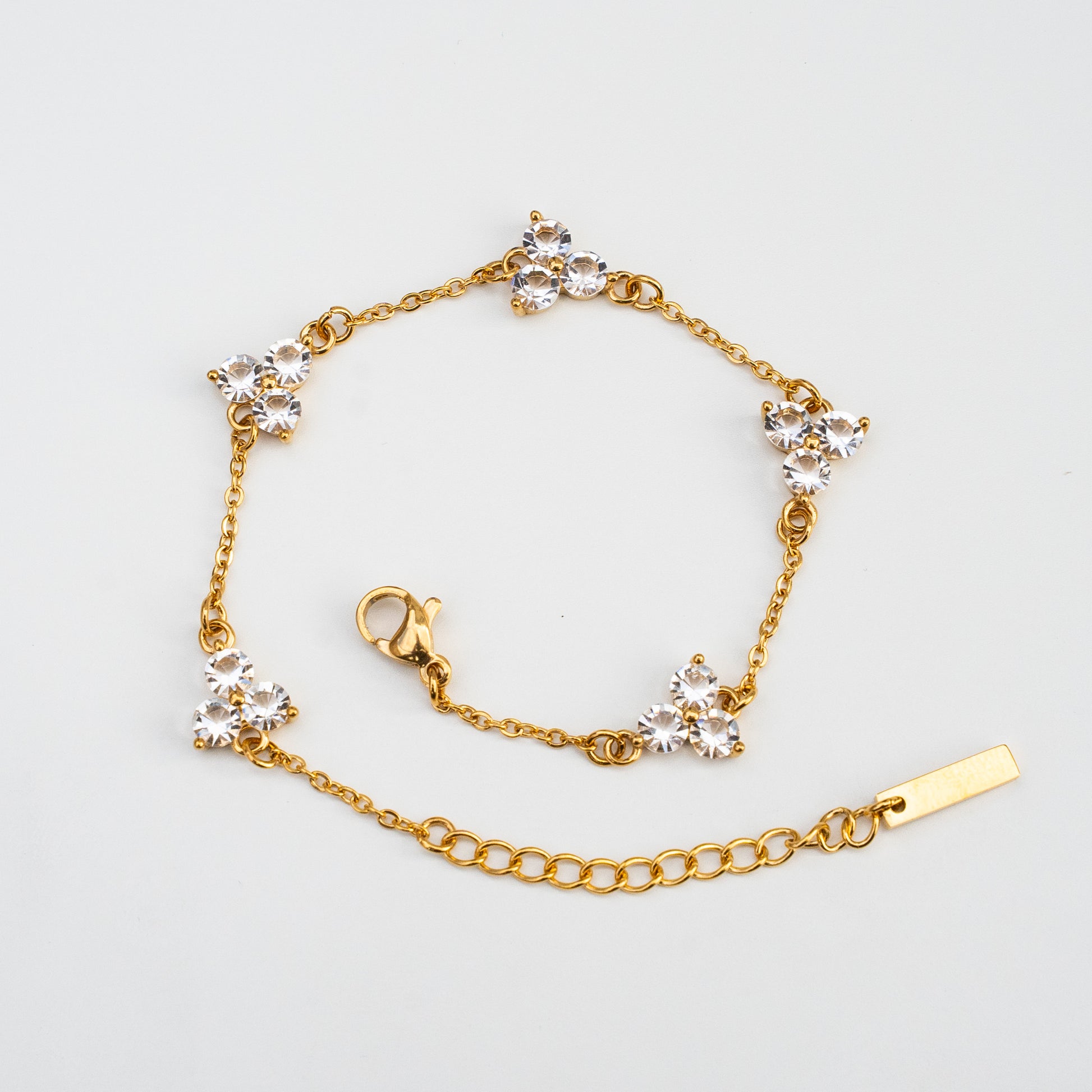 Gold bracelet with diamond-like white gemstones on a light background