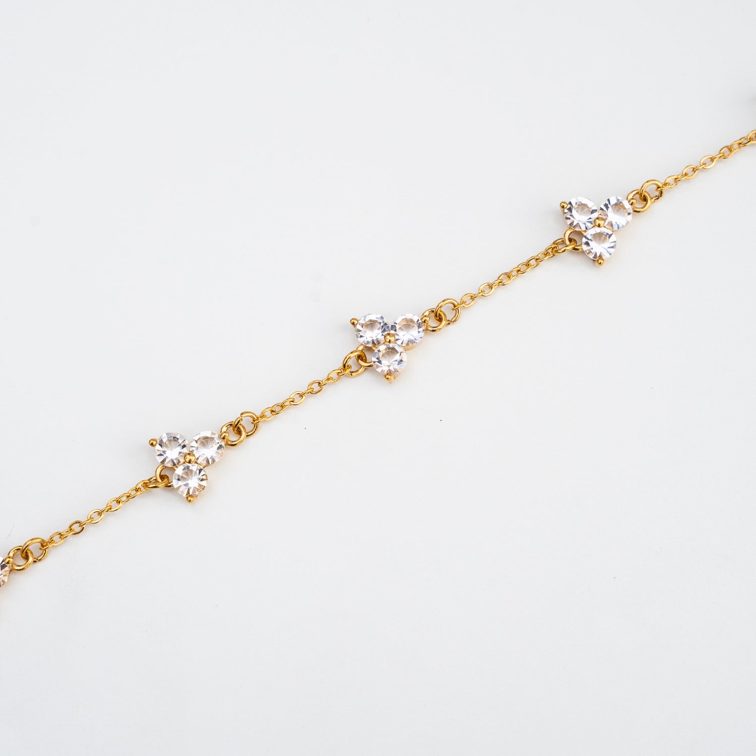 Gold bracelet with small diamond-like white gemstones on a light background