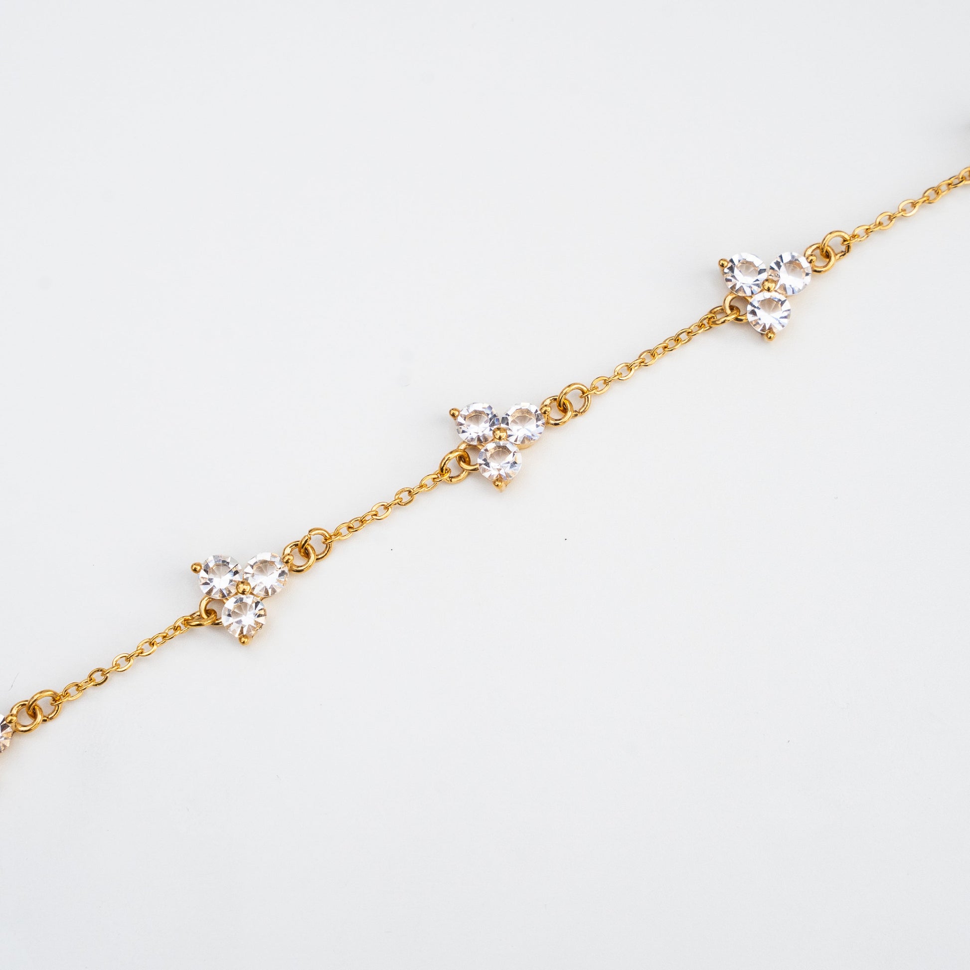 Gold bracelet with small diamond-like white gemstones on a light background