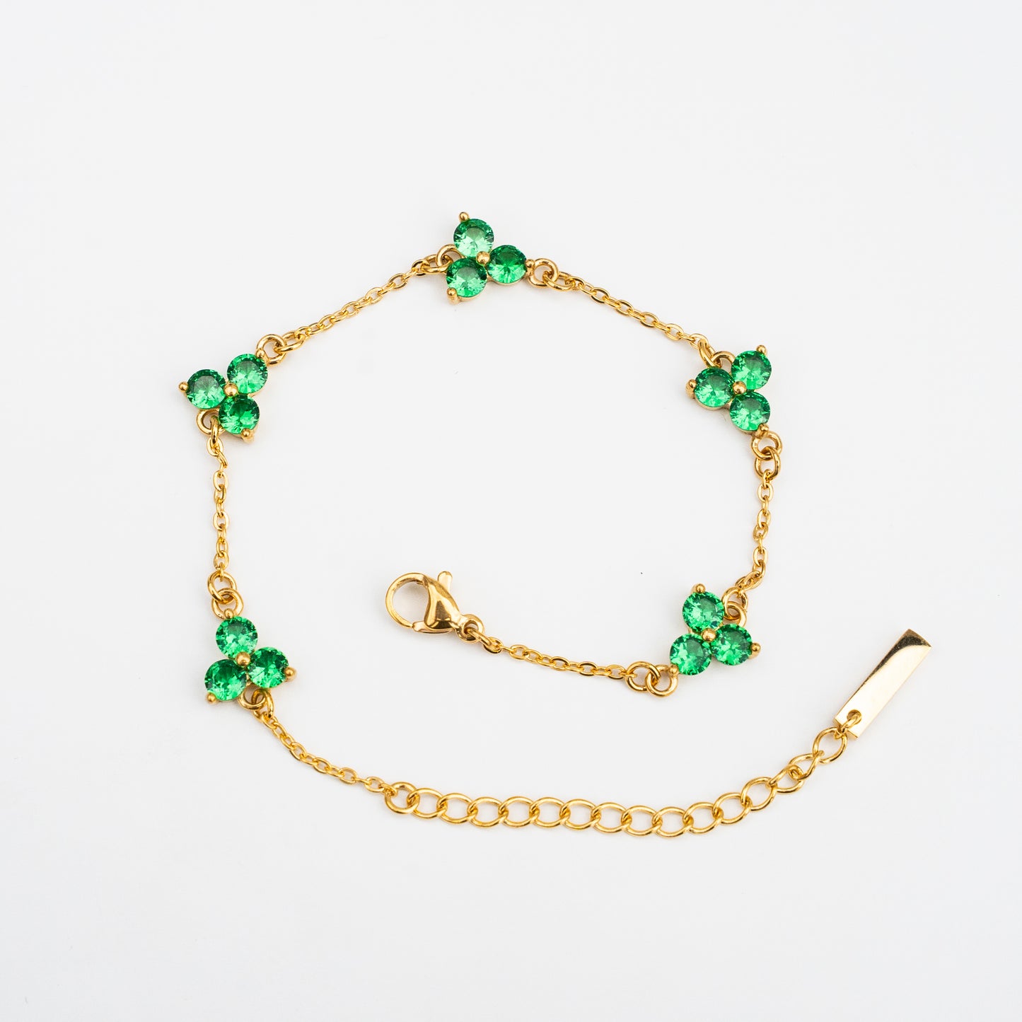 Gold bracelet with green gemstones on a background