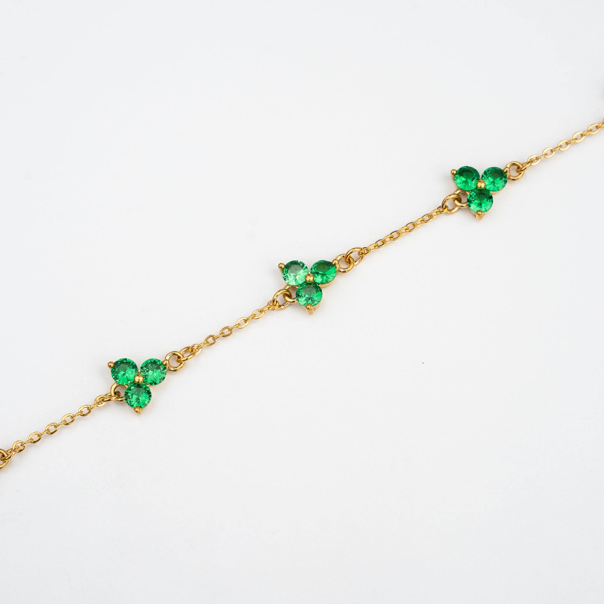 Gold bracelet with green gemstones on a background