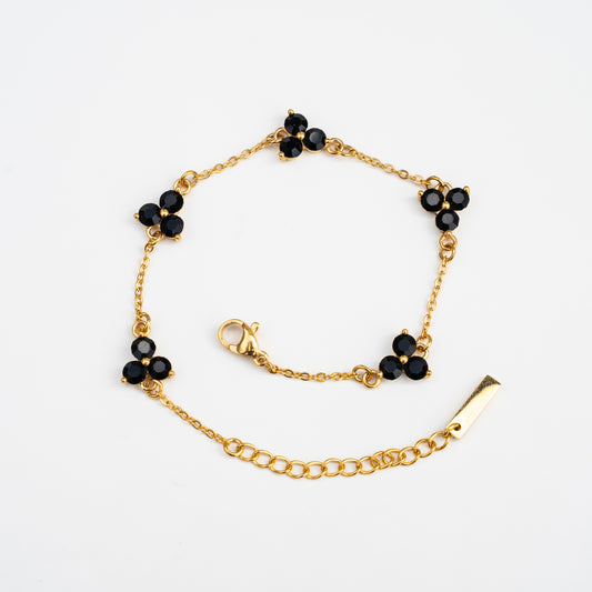 Gold bracelet with black gemstones on a background