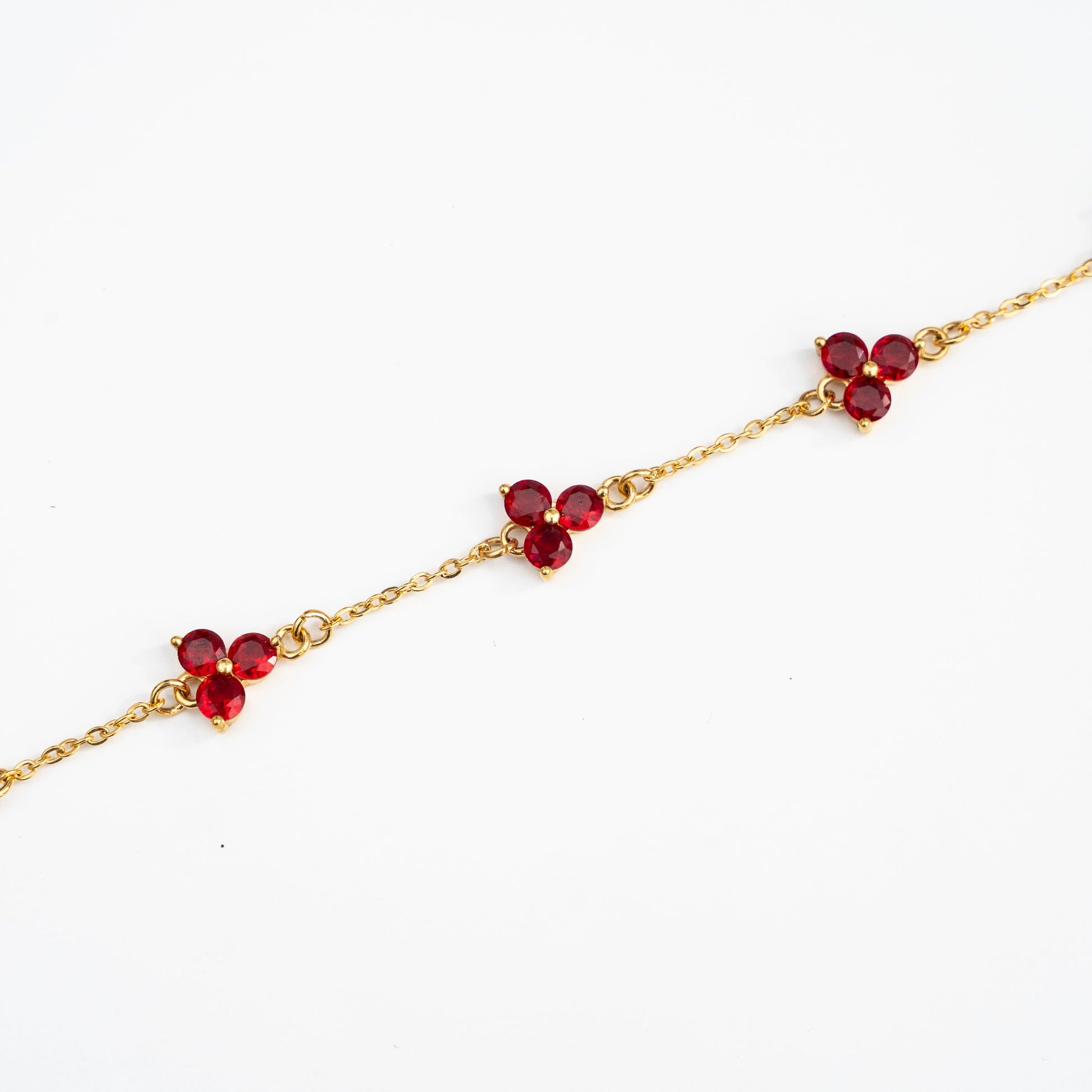 Gold bracelet with red gemstones on a background
