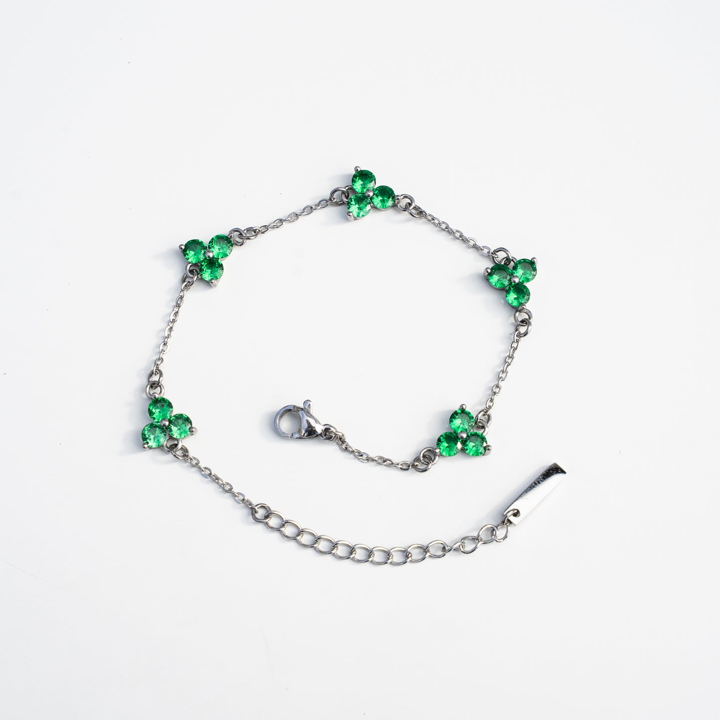 Silver bracelet with green gemstones on a background
