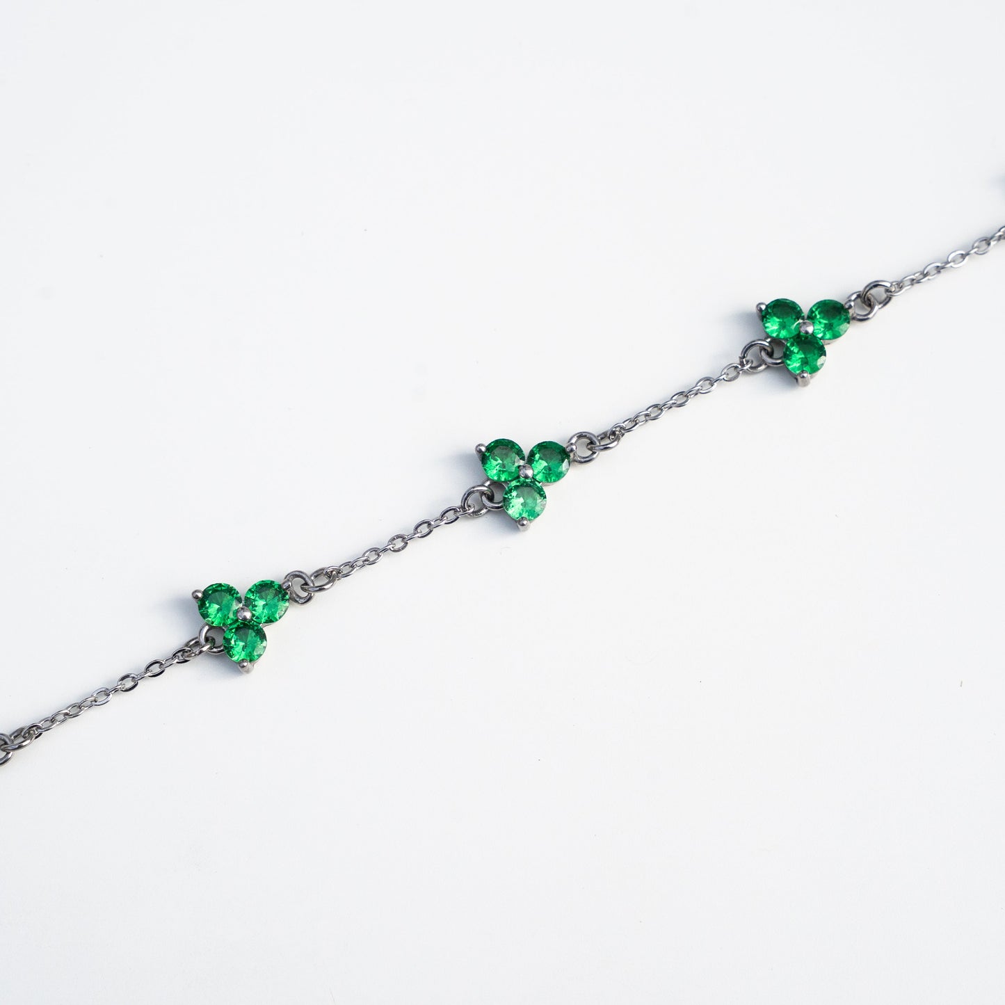 Silver bracelet with green gemstones on a background