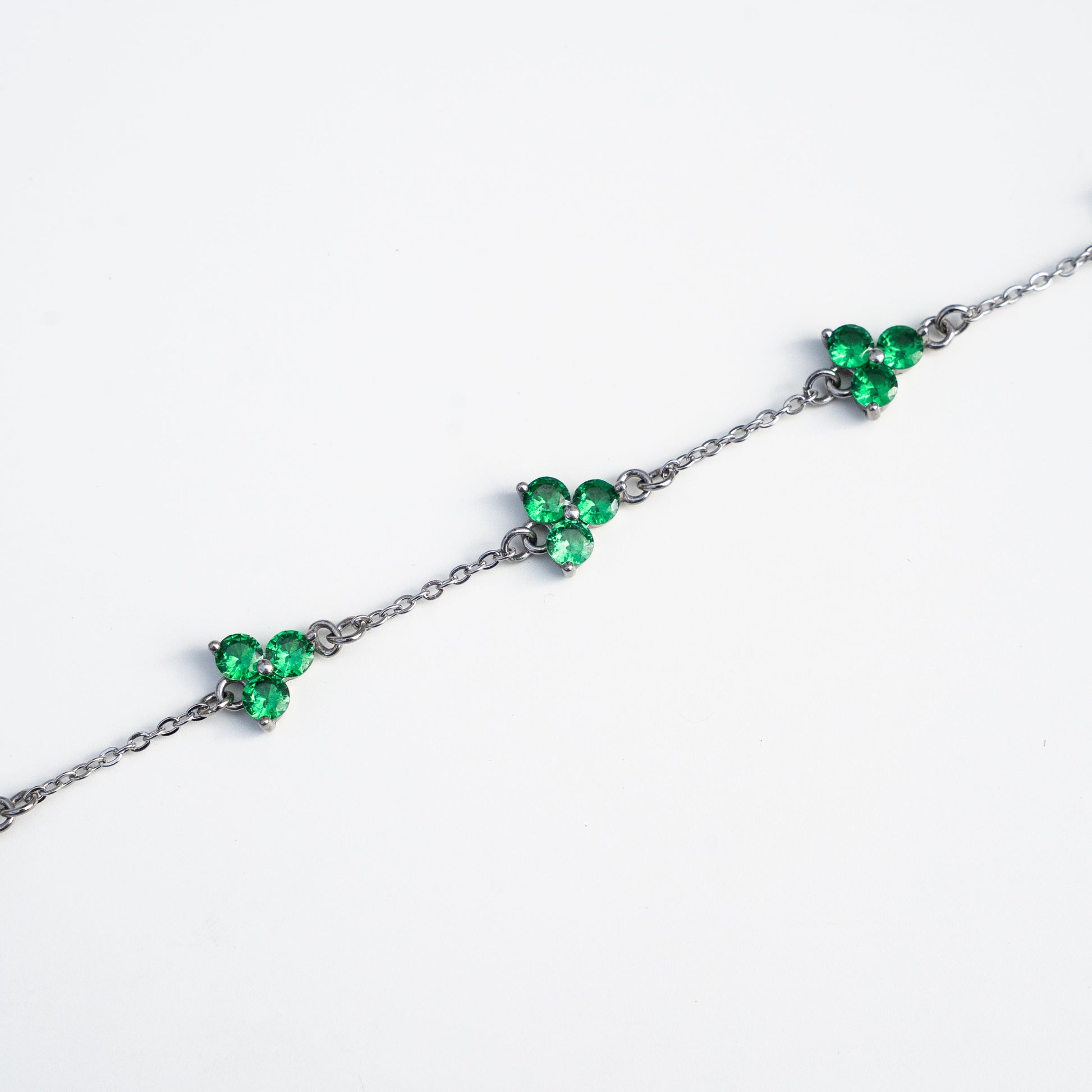 Silver bracelet with green gemstones on a background