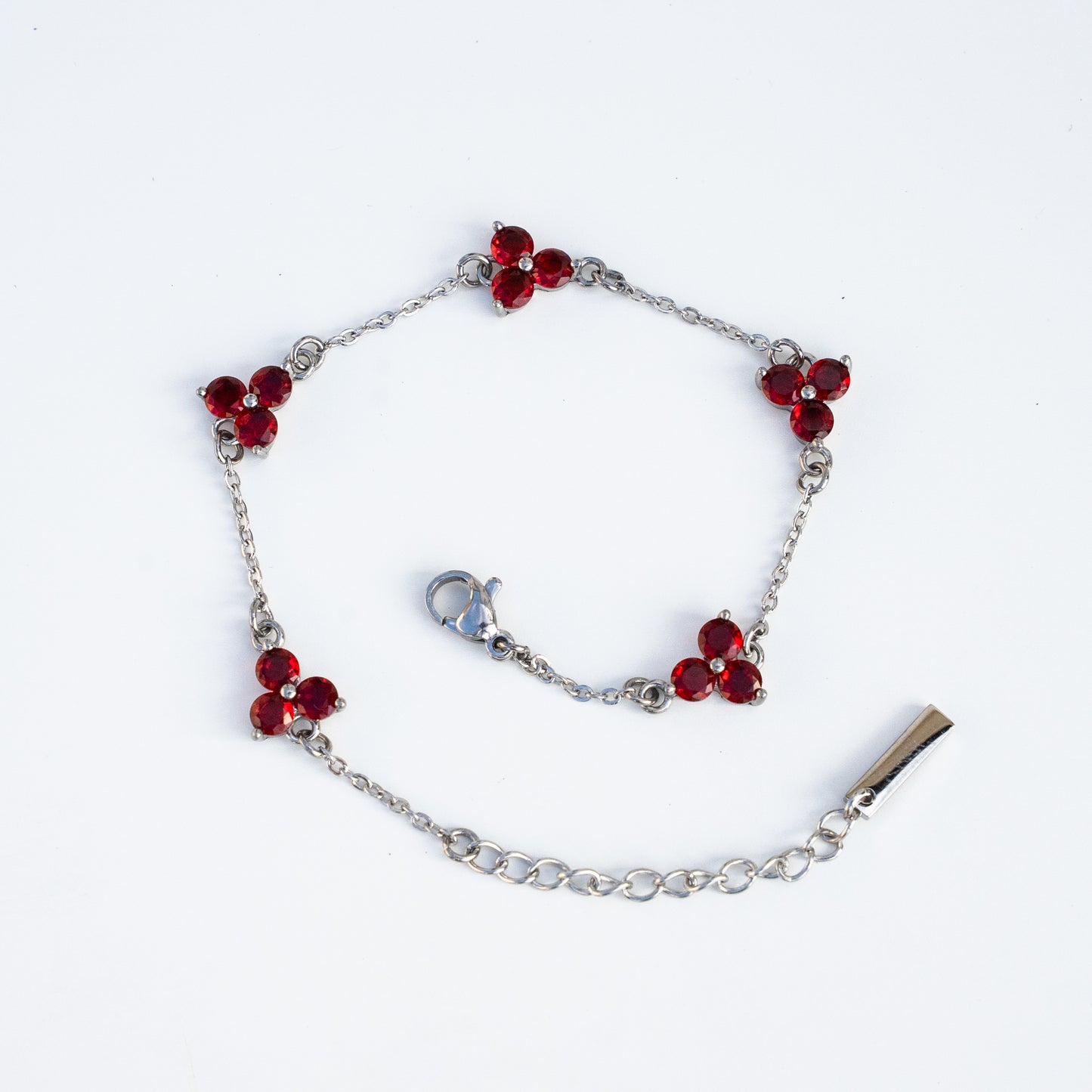 Silver bracelet with red flower-shaped charms on a background