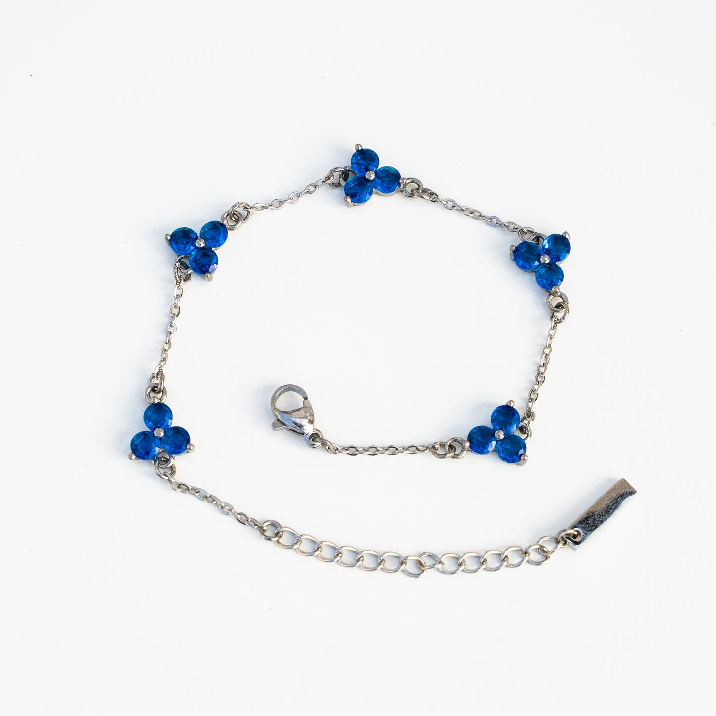 Silver bracelet with blue flower-shaped gemstones on a background