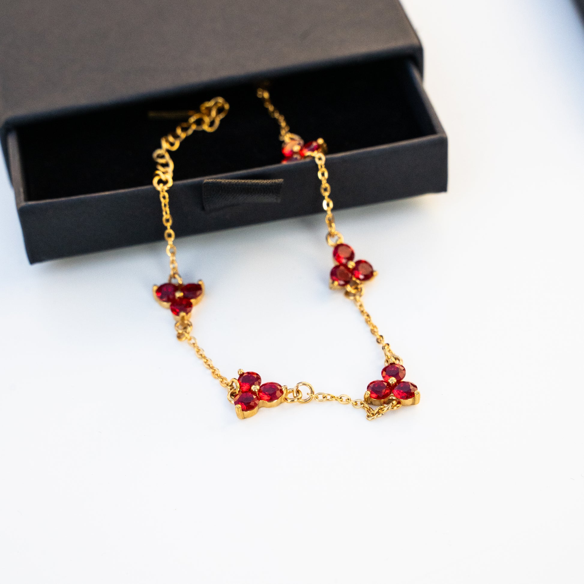 Gold necklace with red gemstones on a surface