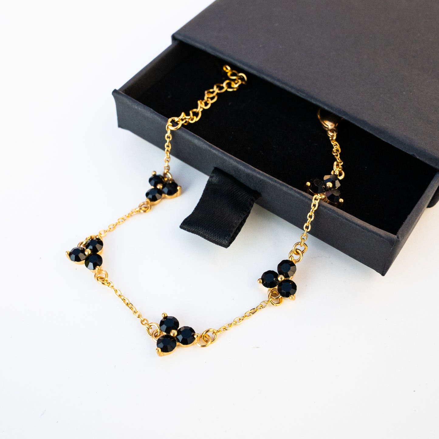 Gold necklace with black gemstones in a black jewellery box on a background