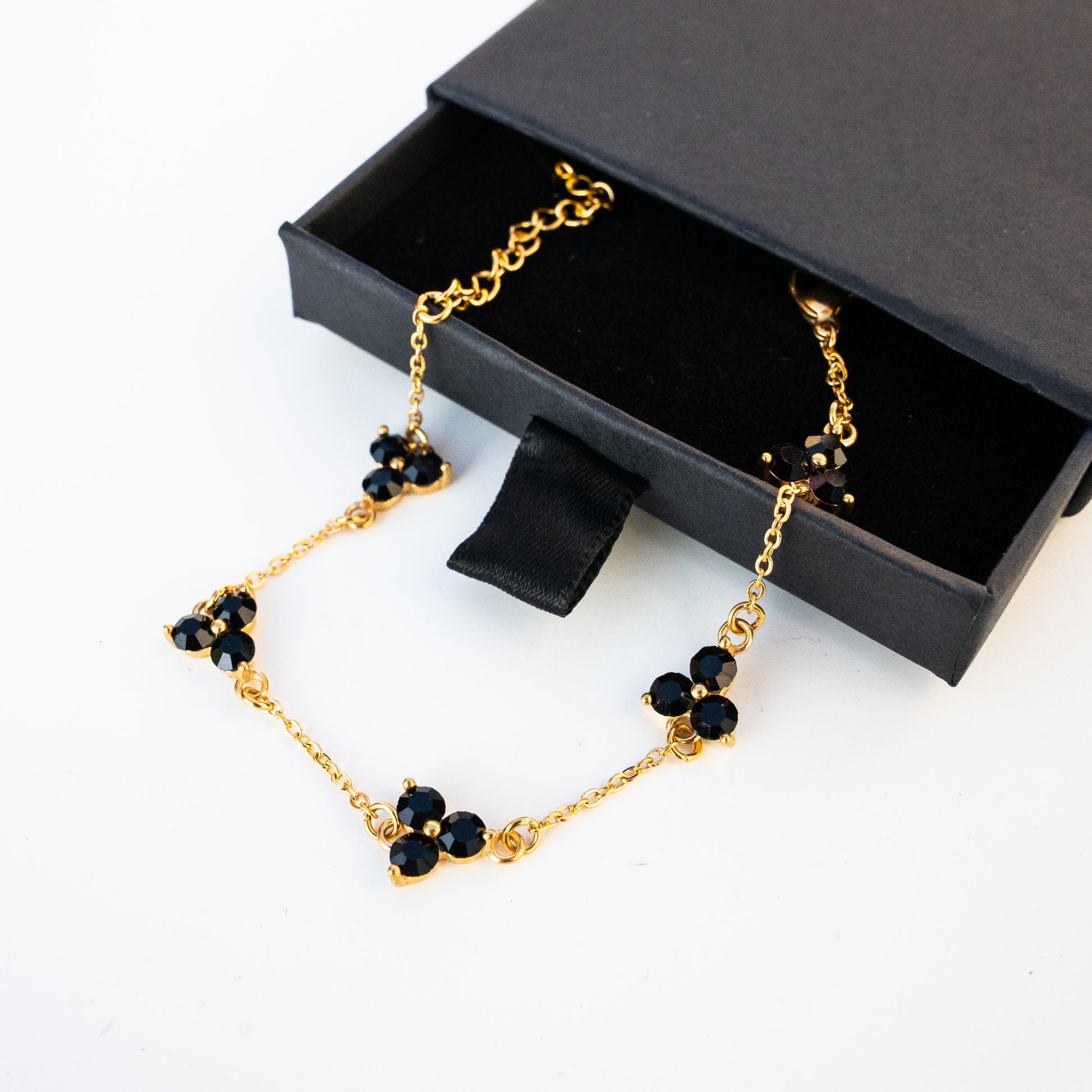 Gold necklace with black gemstones in a black jewellery box on a background