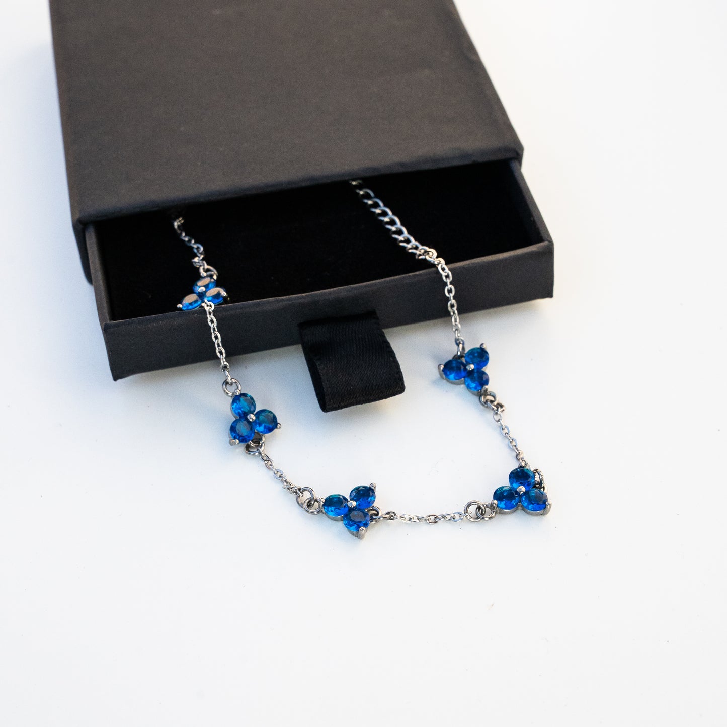 Silver Necklace with blue gemstones in an open jewelry box on a background