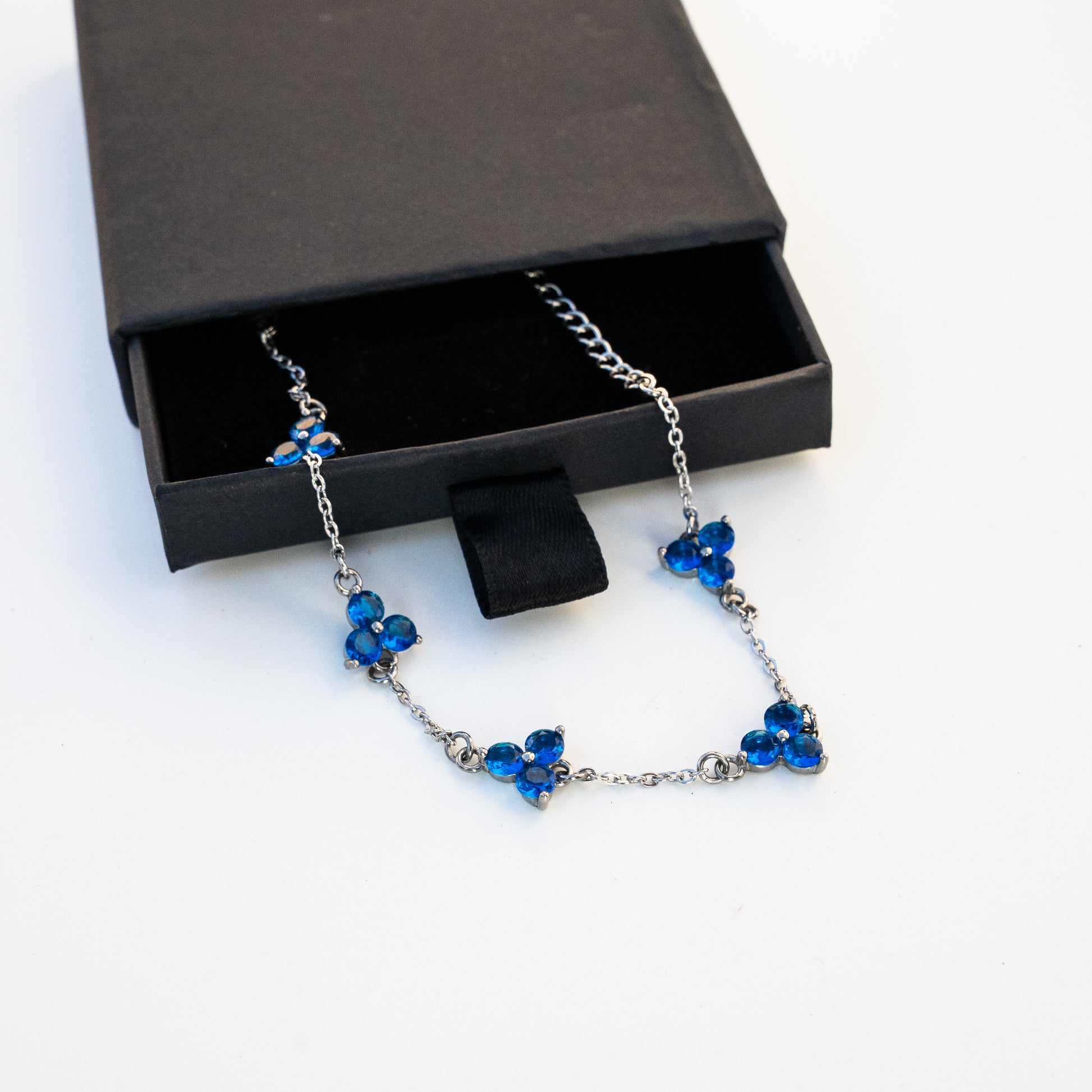 Silver Necklace with blue gemstones in an open jewelry box on a background