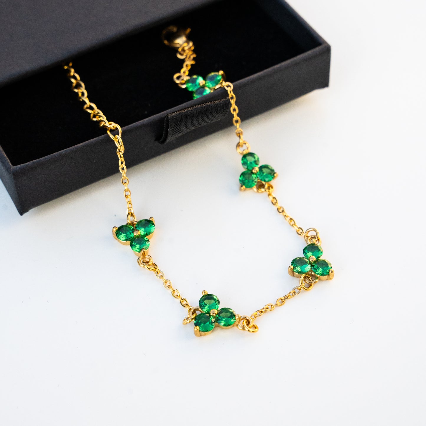 Gold necklace with green gemstones on a surface