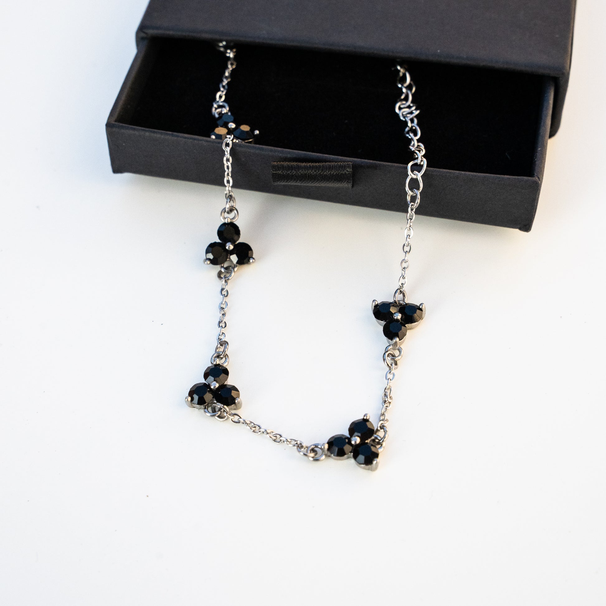 Necklace with black gemstones in front of a black box on a background