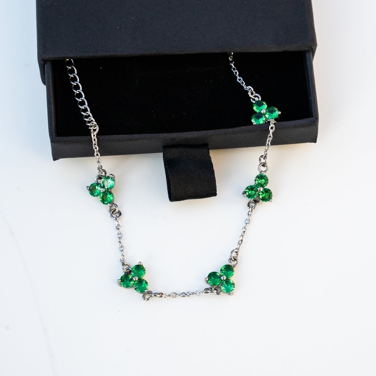 silver Necklace with green gemstones on a box background