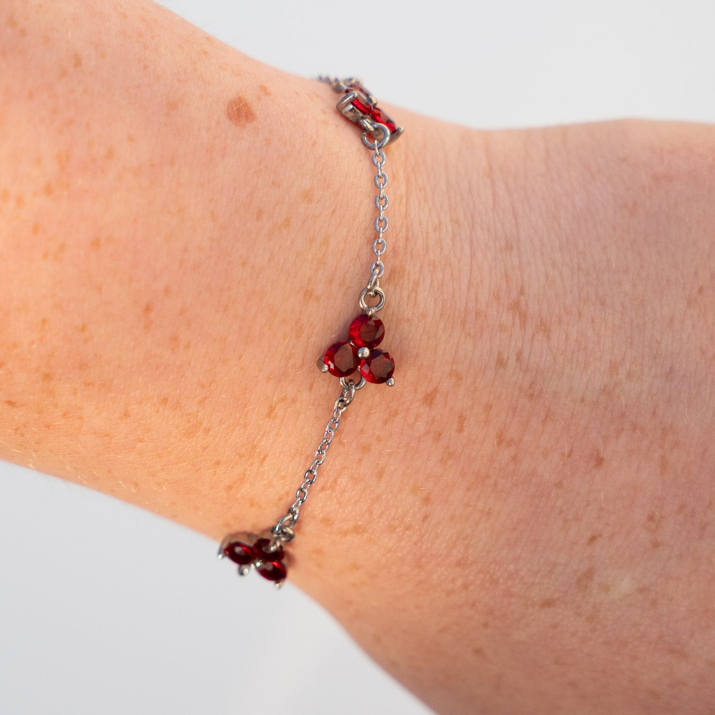 silver Bracelet with red gemstones on a wrist against a neutral background