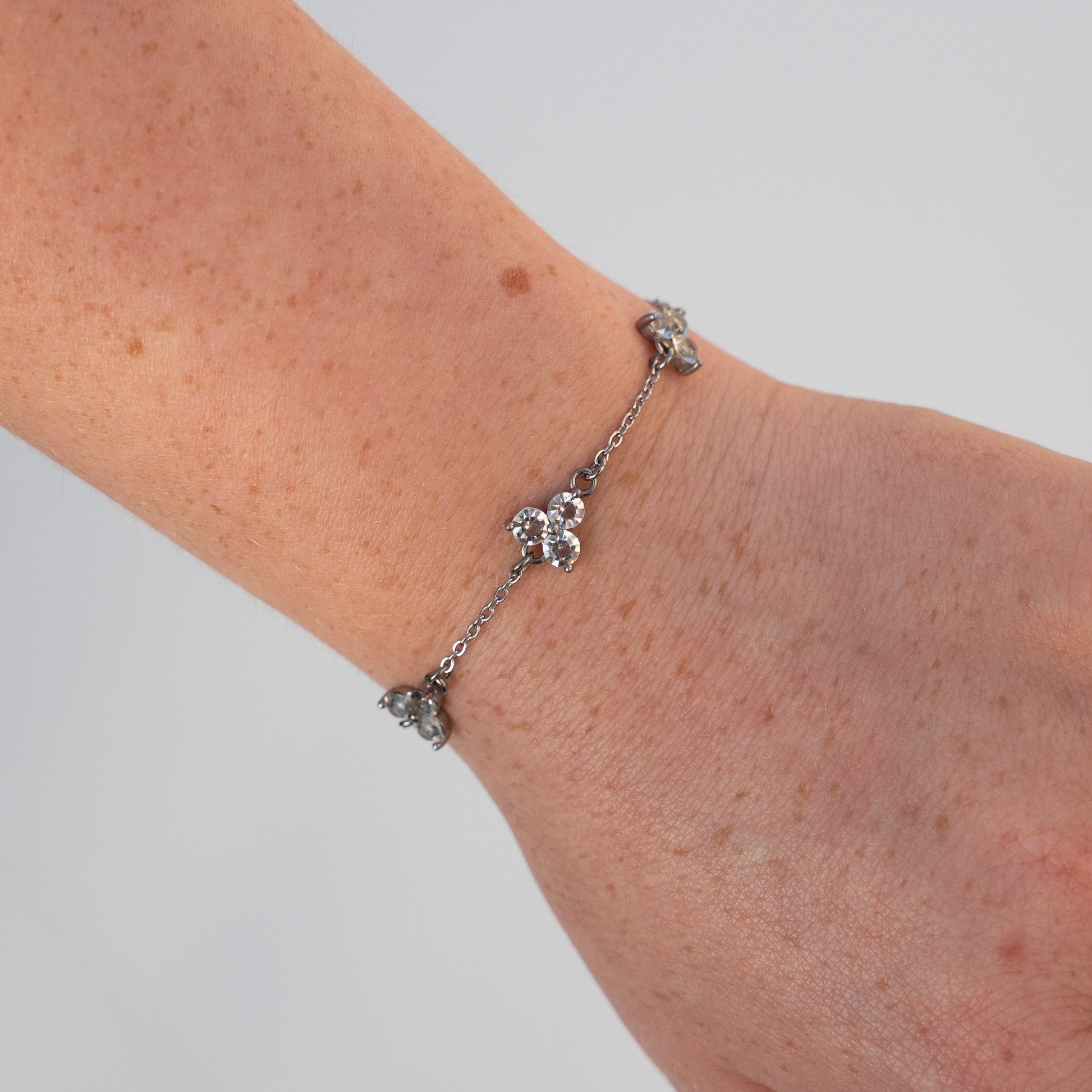 Silver bracelet with white gemstones on a wrist against a light background