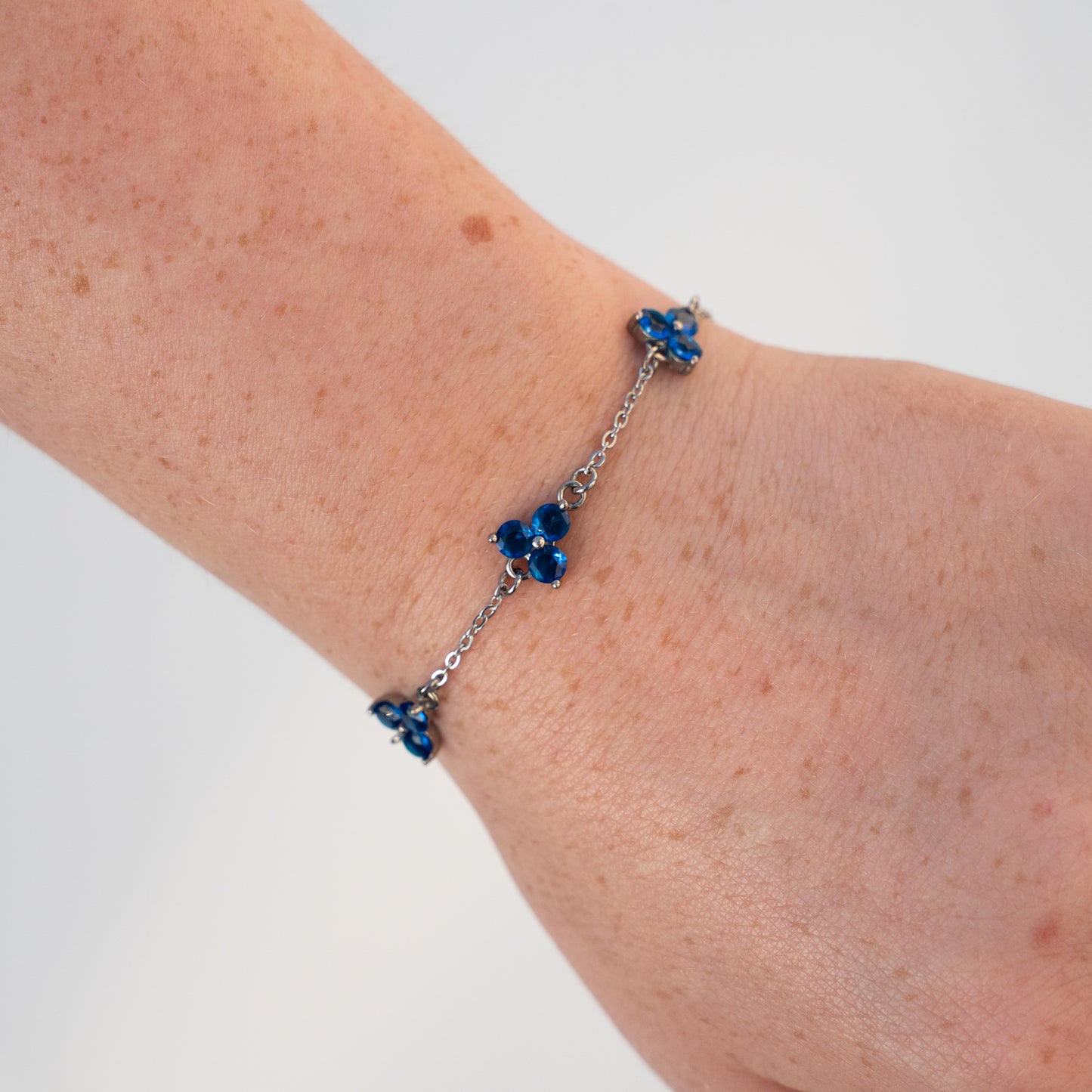 Silver bracelet with blue gemstones on a wrist against a background